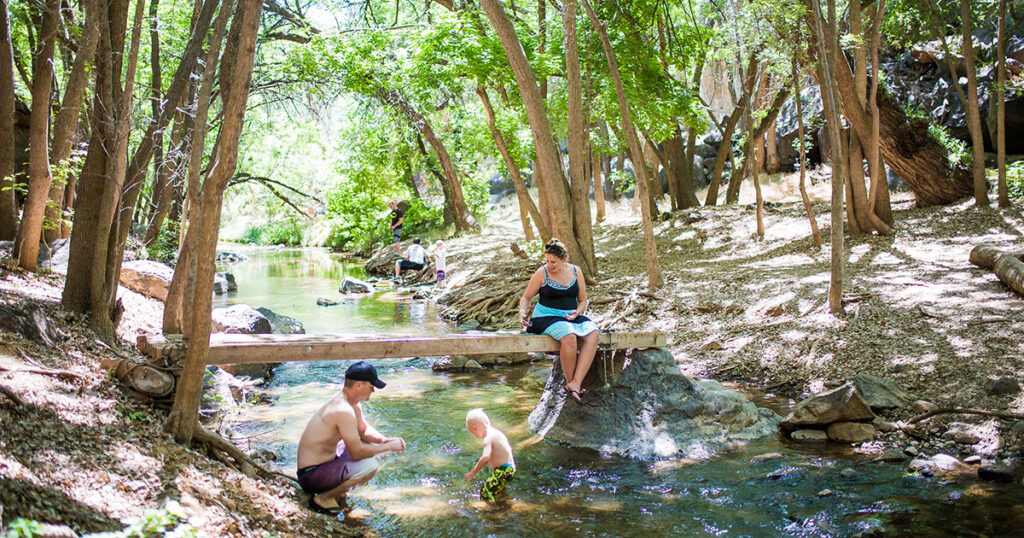 A family enjoying playing and relaxing in the Santa Clara river at Veyo Pool